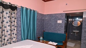 Ein Hotelzimmer mit einem Bett, einer Bank, einem Badezimmer mit Spiegel und Waschbecken sowie einer Tür zu einem weiteren Raum.