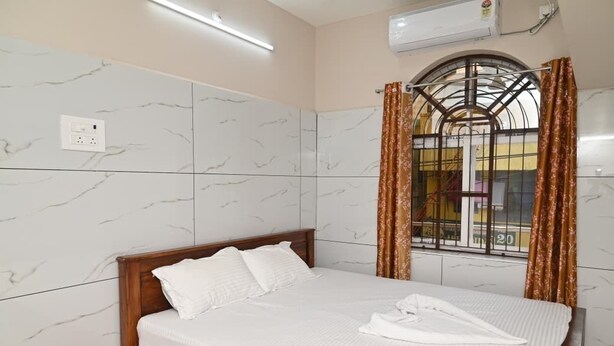 Ein Hotelzimmer mit einem Bett, einem roten Eimer und einem Fenster mit Vorhängen.