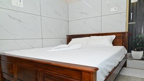 Ein ordentlich bezogenes Bett in einem Zimmer mit einer Wand im Marmoroptik und einem Holzkopfende.