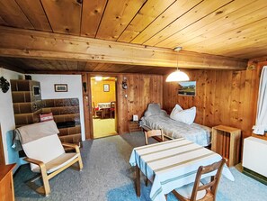 Ein Holzinterieur mit einem Bett, einem Sofa, einem Tisch und einem Stuhl.