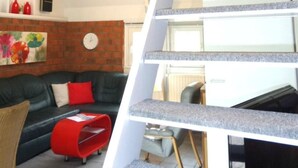 A modern interior with a white staircase, a black leather sofa, and a red accent piece. - 107 Cosima by Interhome (Anjum)