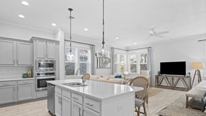 Une cuisine moderne avec des meubles blancs, un îlot central et des appareils électroménagers en acier inoxydable.