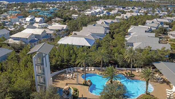 Un quartier résidentiel doté d’une piscine, entourée de chaises longues et de palmiers.