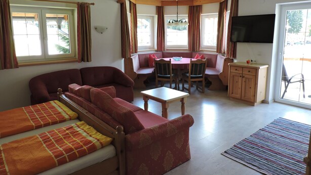 Een gezellige kamer met een bank, een kleine tafel, een bankje en een televisie.