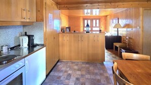 Una cocina acogedora de estilo cabaña con armarios de madera, una estufa y un comedor con mesa y sillas.
