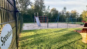 Ein Spielplatz mit Rutsche, Schaukeln und einem eingezäunten Bereich.