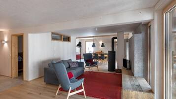 Un salon moderne avec un canapé gris, un tapis rouge et un plancher en bois.