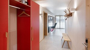 A hallway with a red wardrobe, a wooden bench, and a wall-mounted deer head decoration. - Bellezza - Bio Bergün by Interhome (Bergün)