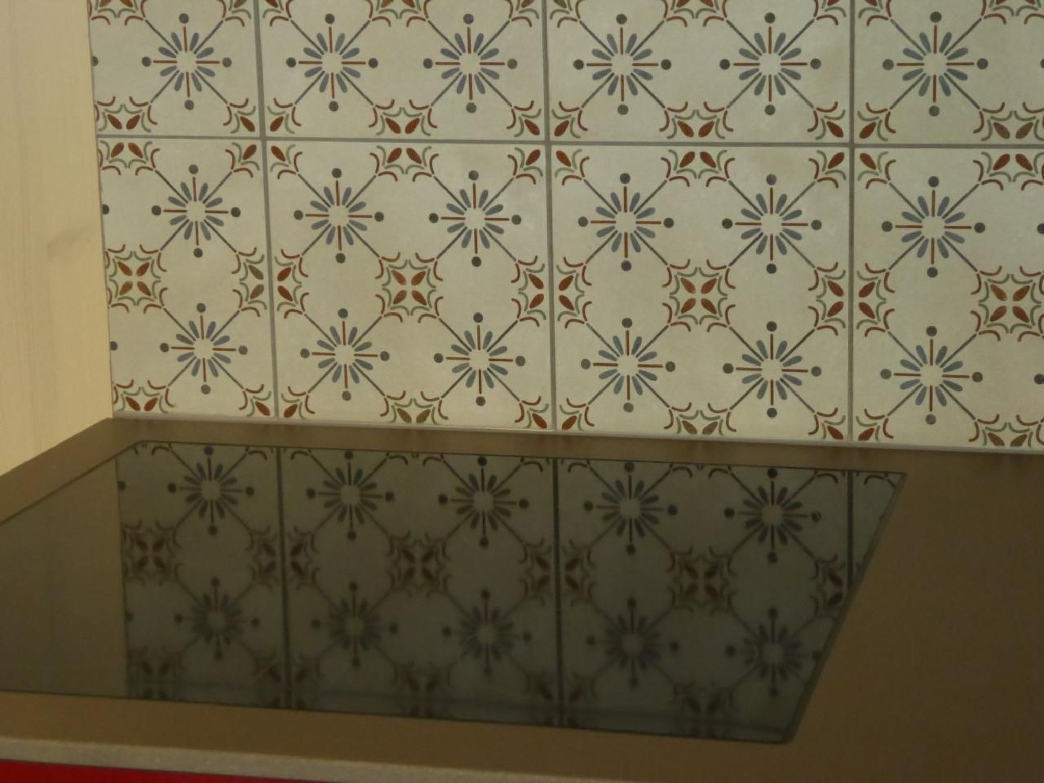 A tiled wall with a geometric pattern and a glass panel below.