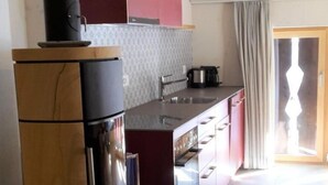 Una cocina moderna con estufa integrada, un lavamanos y un ventanal con cortinas.
