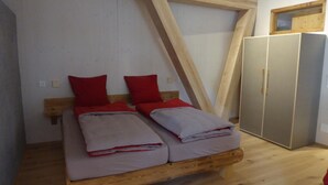 Un dormitorio con una cama de madera, almohadas rojas y un armario.