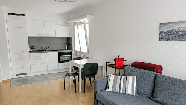 Un espacio habitable compacto con kitchenette, comedor y sofá.