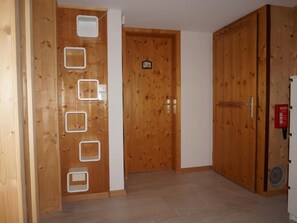 A wooden door with a white handle, a white wall with a small picture, and a wooden floor. - Casa Sagogn Laax by Interhome (Sagogn)