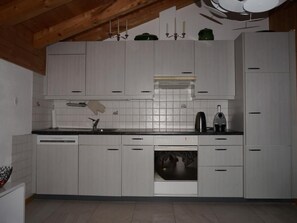 A kitchen with white cabinets, a black countertop, and a built-in oven. - Casa Sagogn Laax by Interhome (Sagogn)