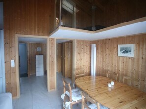 A wooden-paneled room with a dining table, chairs, a refrigerator, and a framed picture on the wall. - Casa Sagogn Laax by Interhome (Sagogn)