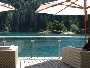 Zona junto a la piscina con vista a un lago y bosque.