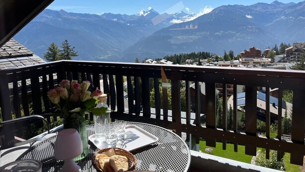 A balcony with a table, a vase with flowers, and a view of mountains. - Helle und moderne Dachwohnung by Interhome (Aminona)