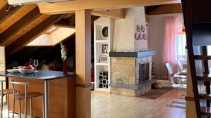 A spacious living area with a wooden ceiling, a stone fireplace, and a dining area with a table and chairs. - Helle und moderne Dachwohnung by Interhome (Aminona)