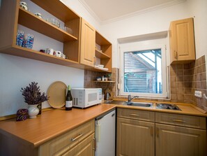 Een koelkast, een microgolfoven, kookgerei, borden en bestek