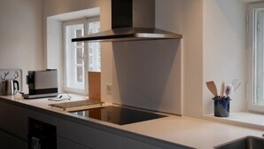 A modern kitchen with a stainless steel range hood, a built-in oven, and a window providing natural light. - Chesa Bindschedler by Interhome (St. Moritz)