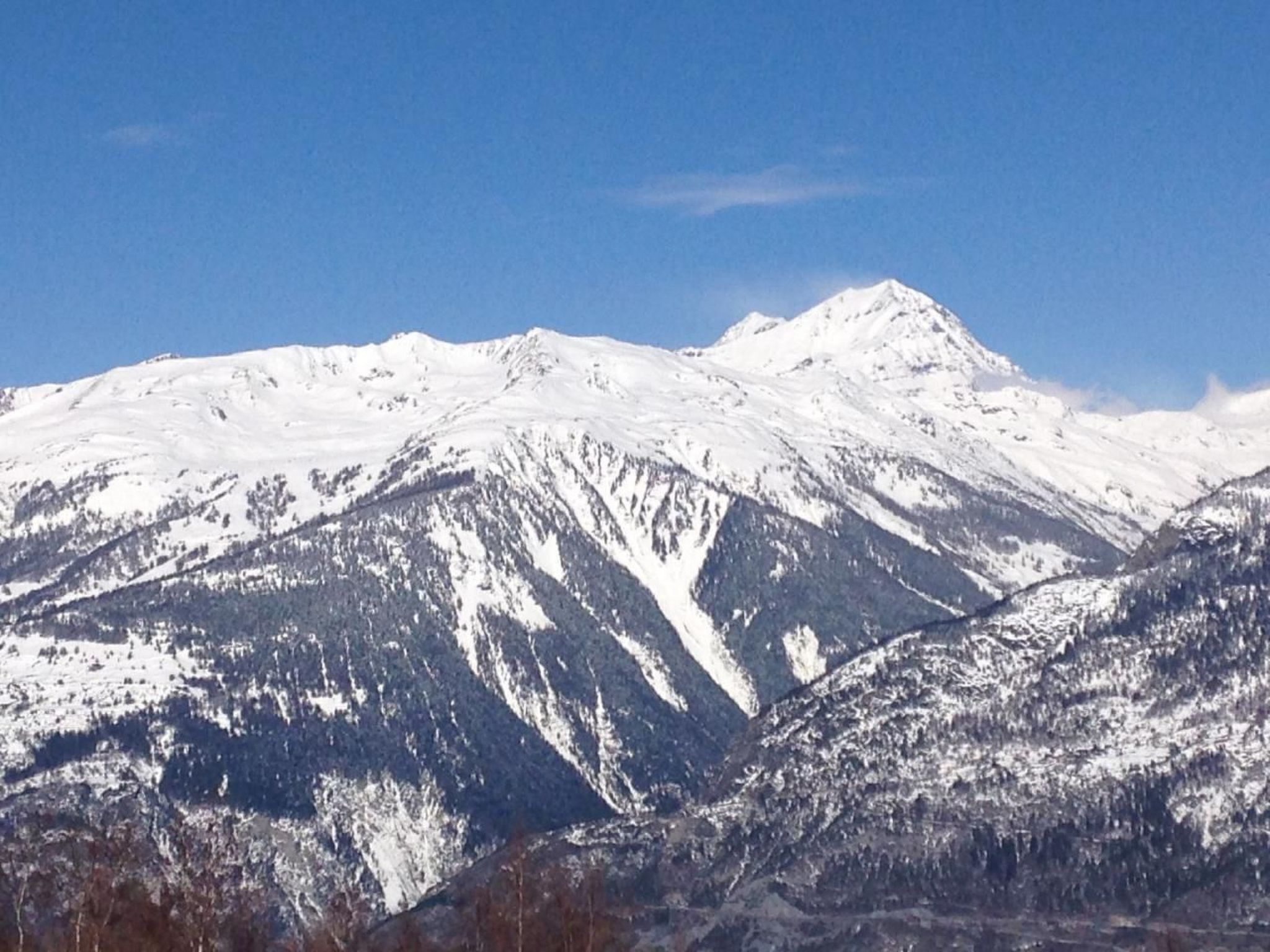 Une chaîne de montagnes enneigée sous un ciel dégagé.