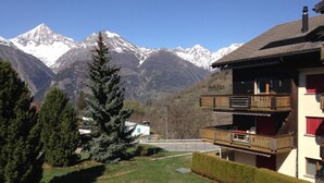 A two-story building with a balcony, set against a backdrop of snow-capped mountains. - in Unterbäch by Interhome (Unterbäch)
