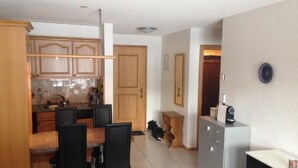 A compact kitchen with wooden cabinets, a dining table with chairs, and a small refrigerator. - in Unterbäch by Interhome (Unterbäch)