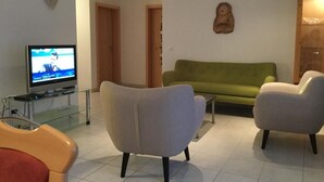 A living room with a television, a green sofa, and two armchairs. - Haus Mondelli by Interhome (Saas-Almagell)