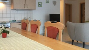 A kitchen with wooden cabinets, a tiled backsplash, a dining table with chairs, and a potted plant. - Haus Mondelli by Interhome (Saas-Almagell)