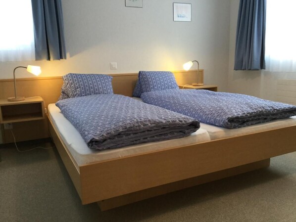 A double bed with a wooden frame, two bedside tables with lamps, and a light-colored carpet.