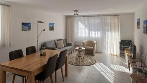 Ein modernes Wohnzimmer mit einem Holzesstisch, einer grauen Couch und einem Fernsehschrank.