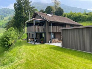 A two-story house with a balcony, a covered porch, and a view of a green landscape. - Wintertschi by Interhome (Weggis)