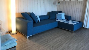Una sala de estar moderna con un sofá azul, una mesita auxiliar y una lámpara.