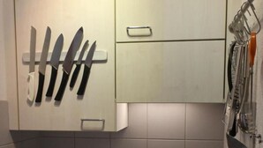 Une cuisine équipée d’un évier en acier inoxydable, d’une cuisinière et de couteaux fixés au mur.