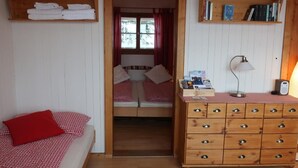 Une pièce confortable avec un lit, une commode et une étagère remplie de livres.