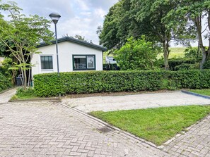 Ett modernt hus med en asfalterad uppfart, en välskött gräsmatta och en häck.
