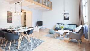 Ein moderner Wohnraum mit Essbereich, einer Couch und einem Fernseher.