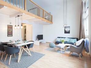 Ein moderner Wohnraum mit Essbereich, einer Couch und einem Fernseher.