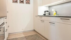 Eine moderne Küche mit weißen Schränken, einem eingebauten Backofen und einem gemusterten Teppich.