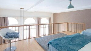 Ein modernes Schlafzimmer mit Balkon, einem Sessel und einem Bett.