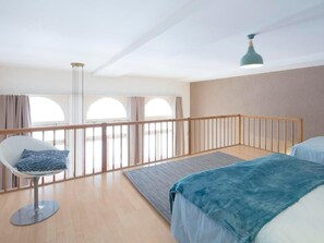 Ein modernes Schlafzimmer mit Balkon, einem Sessel und einem Bett.