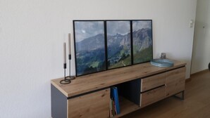 A wooden cabinet with a landscape painting, a candle holder, and a blue bowl. - Siesta 3,5-Zimmer-Wohnung by Interhome (Leukerbad)