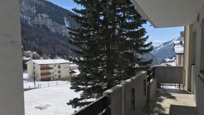 A balcony with a view of a snowy mountain landscape and a building with multiple floors. - Siesta 3,5-Zimmer-Wohnung by Interhome (Leukerbad)