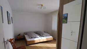 A bedroom with a wooden bed, a chair, and a wardrobe. - Siesta 3,5-Zimmer-Wohnung by Interhome (Leukerbad)