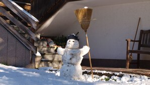 Un muñeco de nieve con una escoba en un paisaje nevado al aire libre.