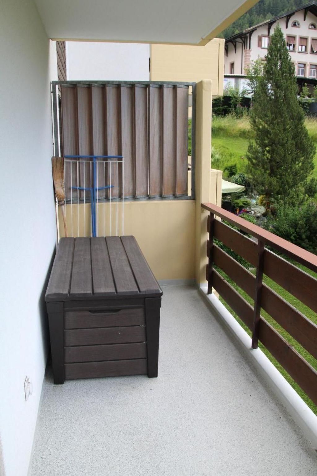 Een balkon met een houten tafel en een metalen leuning.