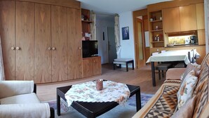 A living room with a sofa, a coffee table, a TV, and wooden cabinets. - Royal 22 nahe Klinik, Burgerbad, Einkaufszentrum by Interhome (Leukerbad)