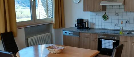 Een koelkast, een oven, een vaatwasser, kookgerei, borden en bestek