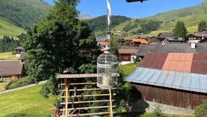 A rural village with traditional wooden houses, a large tree, and a bird feeder. - mit Bergblick by Interhome (Rueras Dieni)