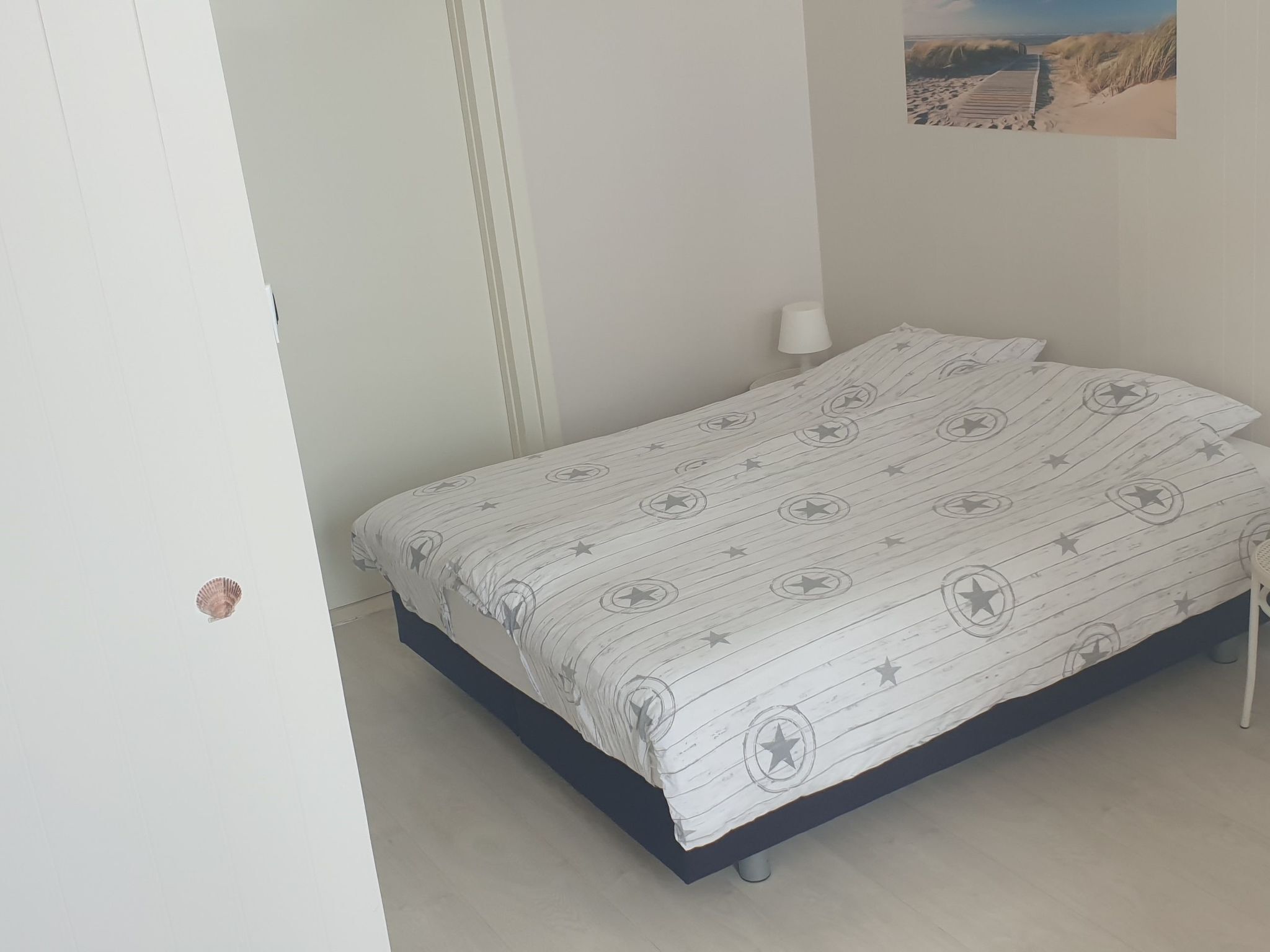 A bedroom with a bed, a nightstand, and a wall-mounted lamp.